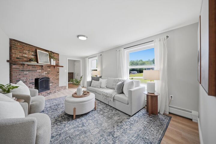 Living room at 7 Twin Street with a large brick fireplace, white seating, and broad windows